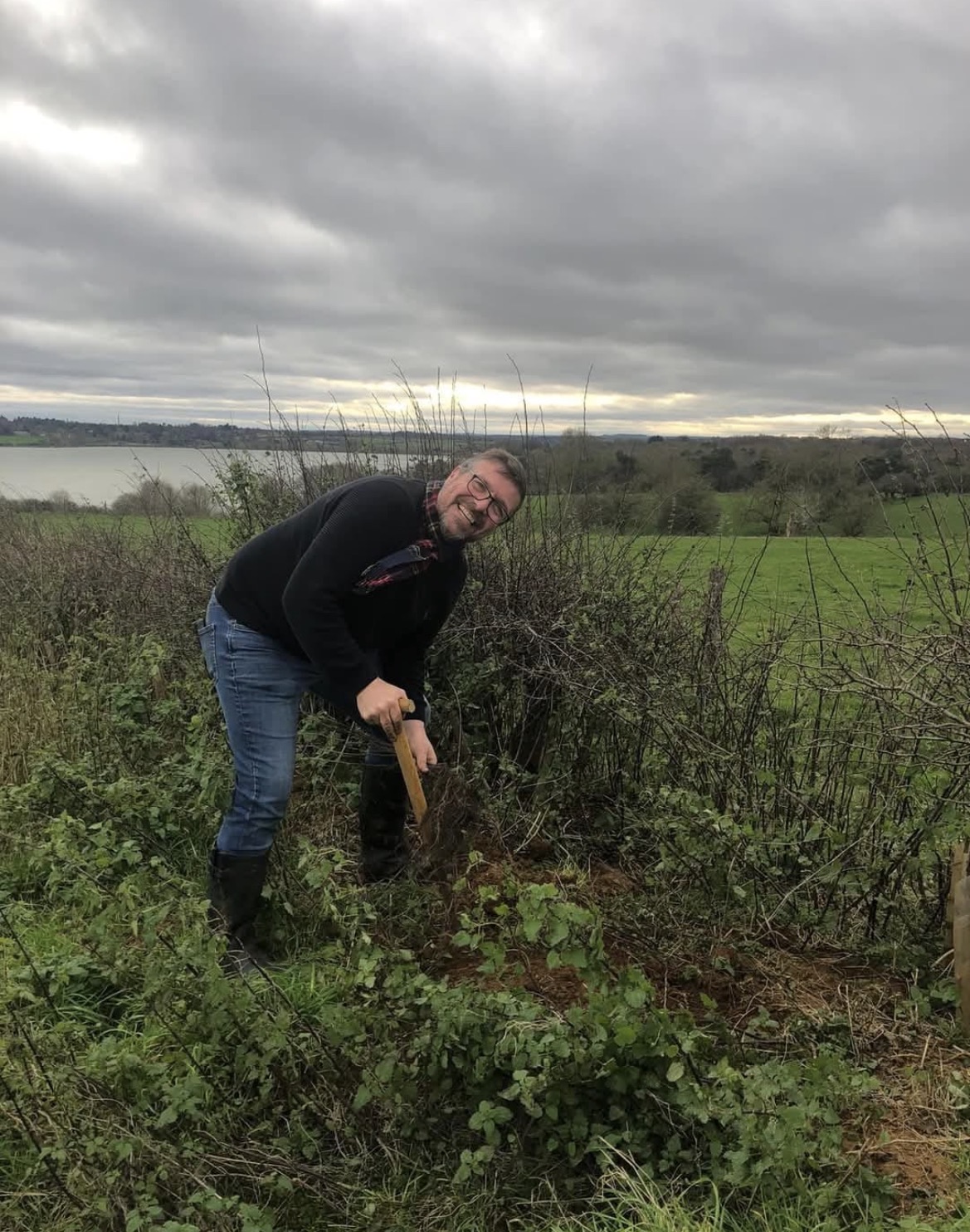 Iain planting a tree in a Northamptonshire hedgerow